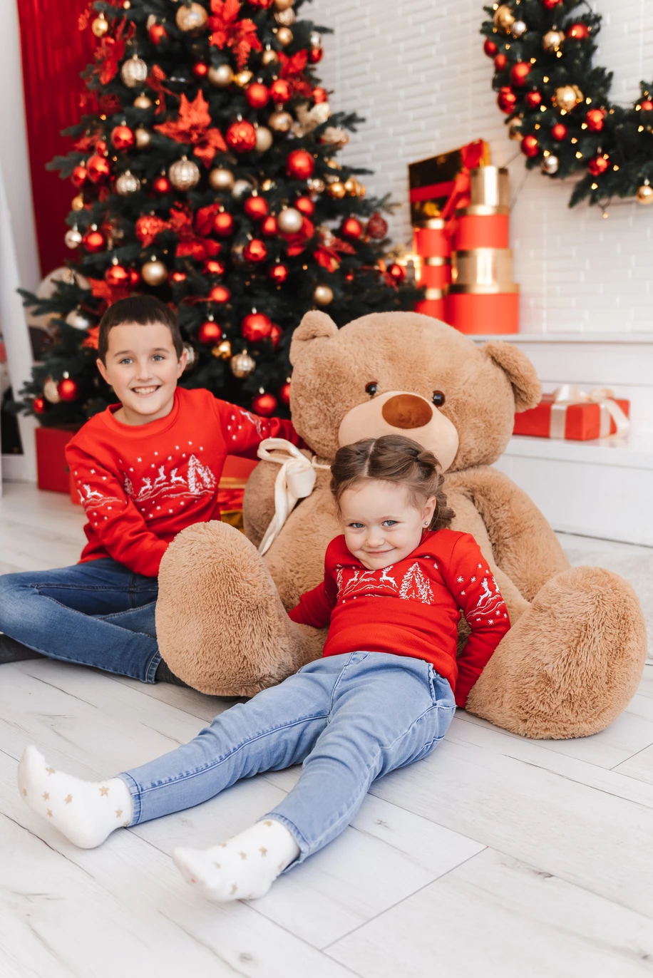 Дитяча радість новорічного свята: гарна дівчинка та хлопчик на фото, у святкових кофтах, виражають щастя та веселощі цього особливого часу